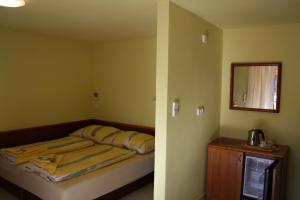 een kleine slaapkamer met een bed en een spiegel bij Penzion Kaminek in Nové Hrady