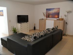 ein schwarzes Ledersofa im Wohnzimmer mit TV in der Unterkunft Apartment FALVIG inkl. Küche in Bad Schonborn