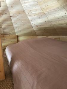 Cama en habitación con techo de madera en Gîte pour 4 personnes, en Saint-Martin-du-Fouilloux