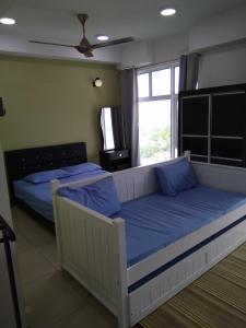 1 dormitorio con 2 camas con almohadas azules y ventana en D'Perdana Apartment 2, en Kota Bharu