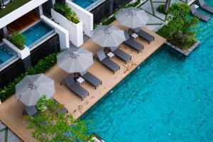 an overhead view of a pool with chairs and umbrellas at G Hua Hin Resort & Mall - SHA Extra Plus in Hua Hin