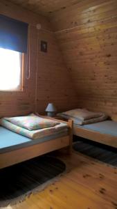 a bedroom with two beds in a wooden cabin at Olszanka in Olchowiec