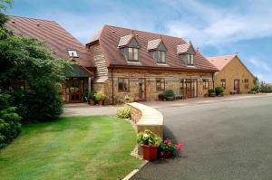 a large house with a road in front of it at Knightcote Farm Cottages in Gaydon