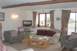a living room with two couches and a tv at Knightcote Farm Cottages in Gaydon