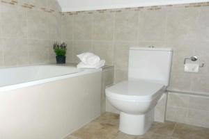 a bathroom with a white toilet and a bath tub at Knightcote Farm Cottages in Gaydon +10 photos