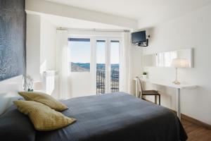 um quarto com uma cama, uma secretária e uma janela em Hotel El Cid em Morella