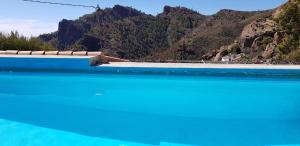 una piscina con agua azul y montañas de fondo en Hoya La Vieja Rural, en Tejeda