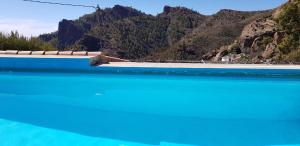 a pool with blue water and mountains in the background at Hoya La Vieja Rural in Tejeda