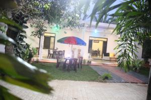 a patio with a table with a red and blue umbrella at Miheen Hotel & Resort - Anuradhapura in Mihintale