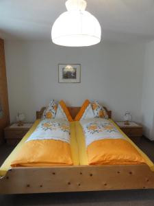 a bedroom with a wooden bed with an orange blanket at Hotel Blümlisalp in Grindelwald