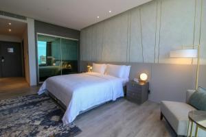 Views Hotel & Residences في King Abdullah Economic City: غرفة نوم بسرير ابيض كبير واريكة