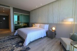 a bedroom with a large white bed and a couch at Views Hotel & Residences - Emaar King Abdullah Economic City in King Abdullah Economic City