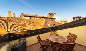 eine Terrasse mit Tisch und Stühlen auf einem Balkon in der Unterkunft Asinelli Panoramic Rooftop, In front of the Two Towers in Bologna