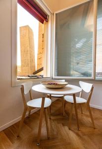 einen Tisch und Stühle in einem Zimmer mit Fenster in der Unterkunft Asinelli Panoramic Rooftop, In front of the Two Towers in Bologna