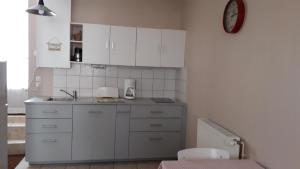 a kitchen with white cabinets and a clock on the wall at le gite de la CURE in Pessac-sur-Dordogne