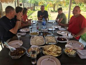 a group of people sitting around a table with food at Aiden Homestay in Pasikuda +36 photos