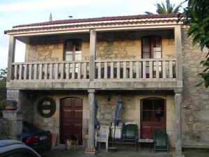 a house with a balcony and a dog standing in front of it at Casa Xan da Pena in Villarmayor