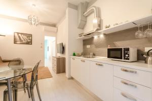 uma cozinha com armários brancos, uma mesa e um micro-ondas em Le Torri Suite, Davanzale vista Due Torri em Bolonha