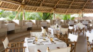 a dining room with white tables and chairs at Gold Zanzibar Beach House & Spa in Kendwa