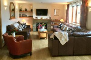 a living room with leather couches and a fireplace at Arbor Holiday Cottages in Southam