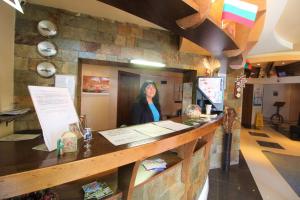 a woman standing behind a counter in a restaurant at Mountview Lodge Apartments in Bansko