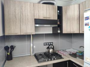 a kitchen with wooden cabinets and a tea kettle on a stove at Квартира in Tiraspol