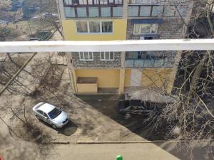 a car parked in front of a yellow house at Квартира in Tiraspol