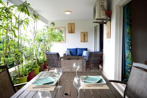 - une table en bois avec des verres à vin sur la terrasse dans l'établissement Kai cosy apartment with terrace pool and sea view near Papeete, à Fa'a'ā