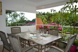 - une table et des chaises en bois sur un balcon fleuri dans l'établissement Kai cosy apartment with terrace pool and sea view near Papeete, à Fa'a'ā