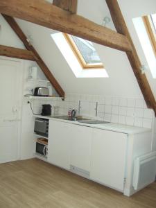 a kitchen with white cabinets and a skylight at Le Rayon Vert in Granville +19 photos