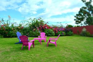 three chairs sitting in the grass in a yard at Villa Tangara - Faa'a - Tahiti - 3 bedrooms - pool and lagon view - 6 pers in Faaa