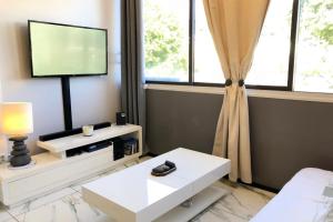 uma sala de estar com uma televisão e um sofá em Ery apartment - Papeete downtown - 2 bedrooms - AC - WiFi - 6 pers em Papeete