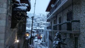 an alley with snow covered buildings and a sign on a building at Alexandros Guesthouse in Arachova