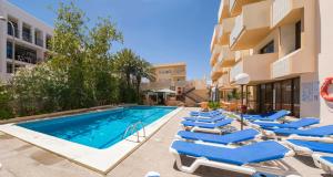 a swimming pool with lounge chairs next to a building at Apartamentos Jovial in San Antonio