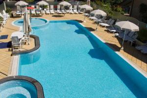uma grande piscina com cadeiras e guarda-sóis em Hotel Rosenblatt em Cervia