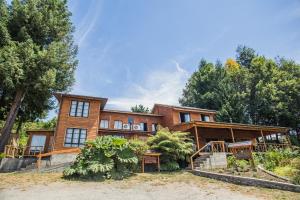 a large wooden house with trees in front of it at Apart hotel Puchaley Lafquen in Panguipulli