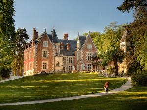 a woman walking down a path in front of a large house at Landreau in La Riche