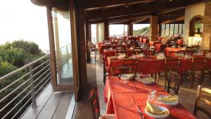 a restaurant with red tables and chairs on a balcony at Hotel Corsaro Nero in Portu Maga