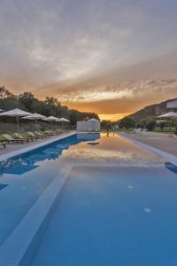 a large swimming pool with a sunset in the background at Olivista Boutique Hotel in Perdika