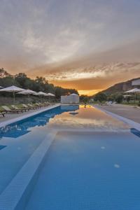 ein großer Swimmingpool mit Sonnenuntergang im Hintergrund in der Unterkunft Olivista Hotel in Perdika