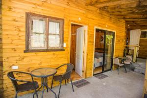 a patio with a table and chairs in a cabin at Refugio Ruka Cümelen in Panguipulli