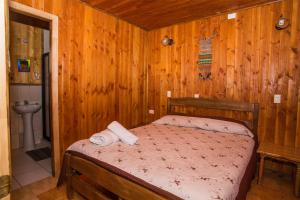 a bedroom with a bed in a room with wooden walls at Refugio Ruka Cümelen in Panguipulli