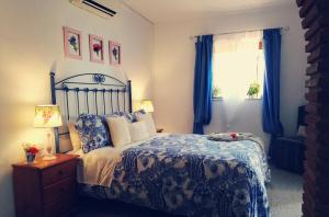 a bedroom with a bed and a window with blue curtains at Cortijo Buenavista in Málaga