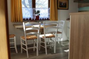 kuchnia ze stołem i 4 białymi krzesłami w obiekcie Apartma Lipa w mieście Mojstrana