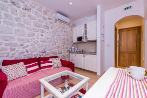 a living room with a red couch and a stone wall at Historical Old town apartments in Dubrovnik