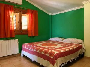 1 dormitorio con 1 cama con paredes verdes y cortinas rojas en Casa Rural LOS CORTESES, en Los Díaz