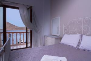 a bedroom with a large bed and a balcony at Villa Skiadeni - Sea front house in Halki +17 photos