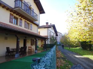 a fence in front of a house with a green lawn at Apartamento Usuaia con jacuzzi in Lesaka