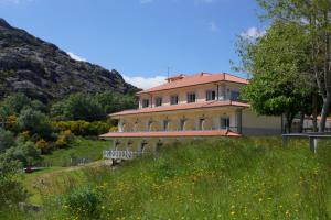 uma casa grande numa colina com um campo de flores em Hotel Miracastro em Castro Laboreiro