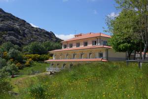 a large house on a hill with a field of flowers at Hotel Miracastro in Castro Laboreiro